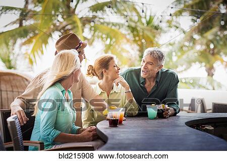 Couples having cocktails at patio bar View Large Photo Image Stock Photo - Couples having cocktails at patio bar. Fotosearch