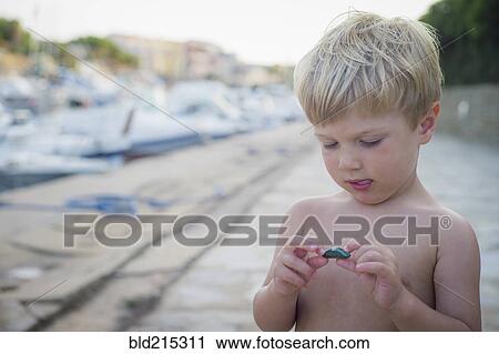 Stock Image - Curious Caucasian boy playing with rock. Fotosearch