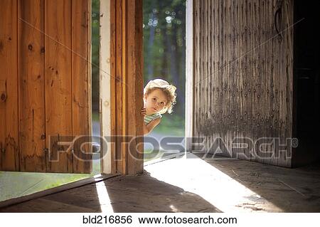 Stock Photograph - Curious girl peering around open door. Fotosearch