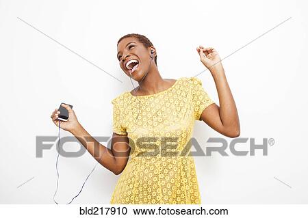 Stock Image - Dancing Black woman dancing to mp3 player. Fotosearch