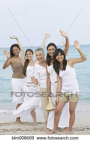 Diverse women standing on beach together waving View Large Photo Image Stock Photo - Diverse women standing on beach together waving. Fotosearch