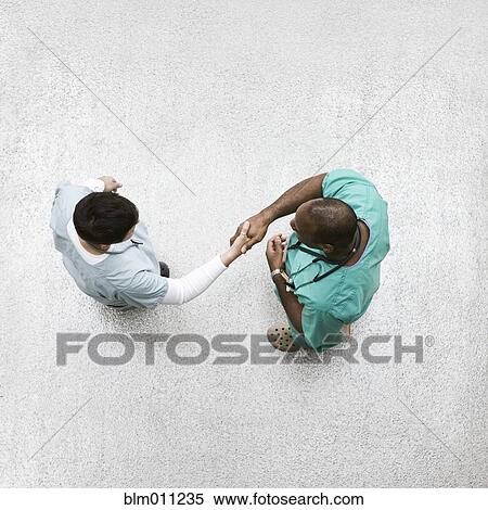 Doctors shaking hands in lobby View Large Photo Image Stock Photography - Doctors shaking hands in lobby. Fotosearch