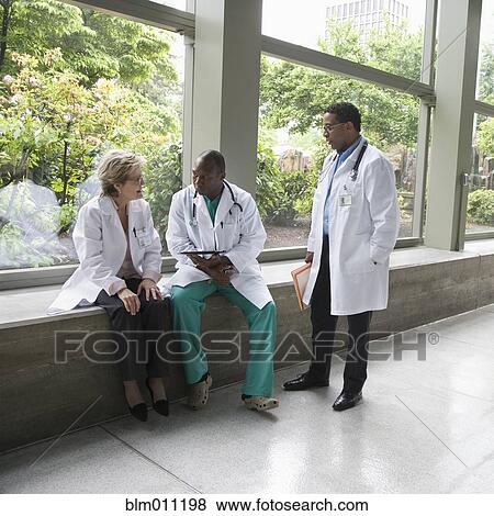 Stock Photo - Doctors talking together in lobby. Fotosearch