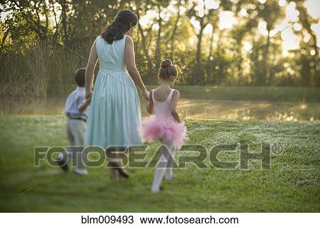 Stock Image - Elegant mother walking outdoors with children. Fotosearch