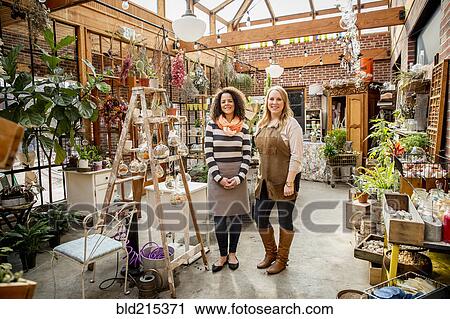 Stock Image - Employee and customer smiling in plant nursery. Fotosearch