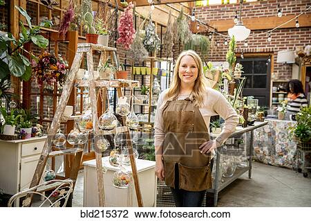 Stock Image - Employee smiling in plant nursery. Fotosearch