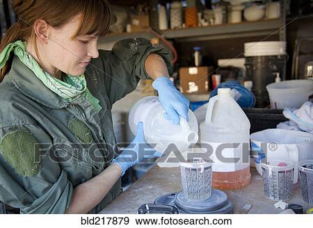 Stock Photo - Entrepreneur pouring liquid in workshop. Fotosearch