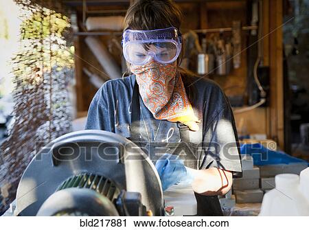 Stock Image - Entrepreneur using machinery in workshop. Fotosearch