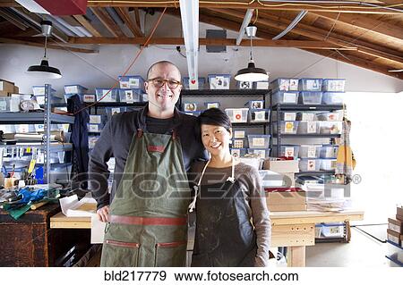 Stock Photo - Entrepreneurs hugging in workshop. Fotosearch