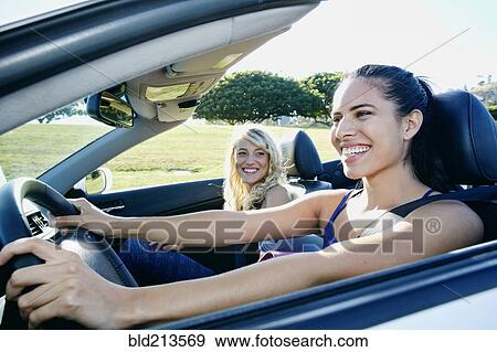 Stock Photo - Excited women driving convertible on road trip. Fotosearch