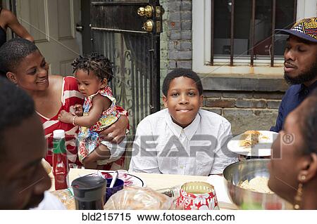 Stock Photography - Family eating together at backyard barbecue. Fotosearch