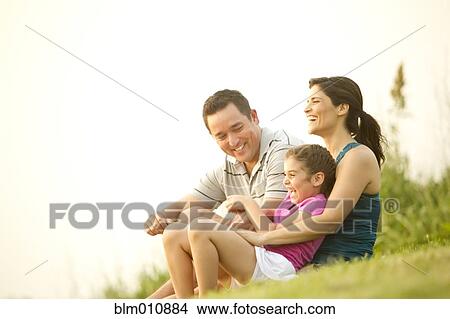 Picture - Family sitting in grass together. Fotosearch