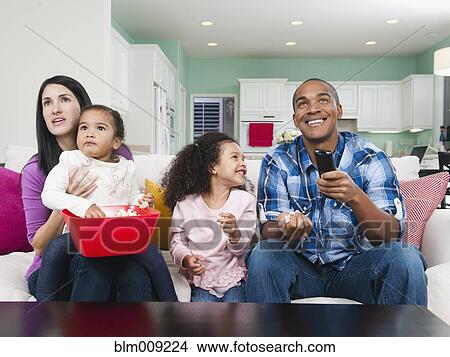 Picture - Family sitting on sofa watching television. Fotosearch