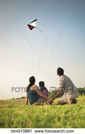 Stock Image - Family watching kite in sky. Fotosearch