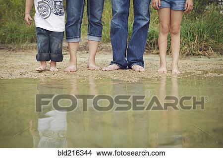 Picture - Family wearing jeans at still puddle. Fotosearch