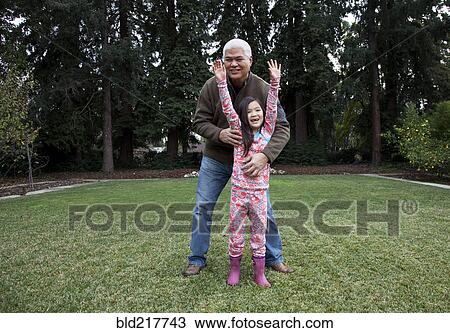 Stock Image - Father and daughter playing in backyard. Fotosearch