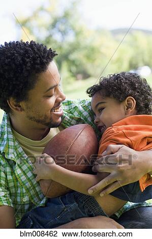 Stock Image - Father and son holding basketball. Fotosearch