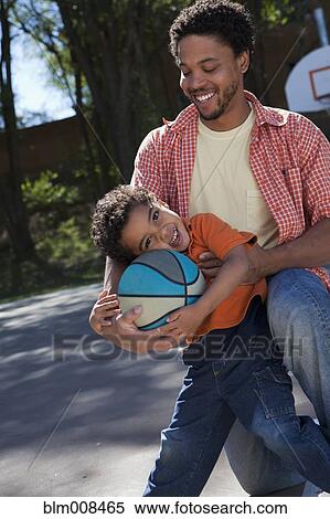 Stock Photography - Father and son holding basketball. Fotosearch