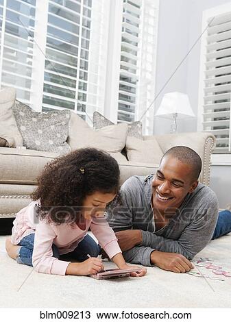 Stock Image - Father watching daughter play video game. Fotosearch