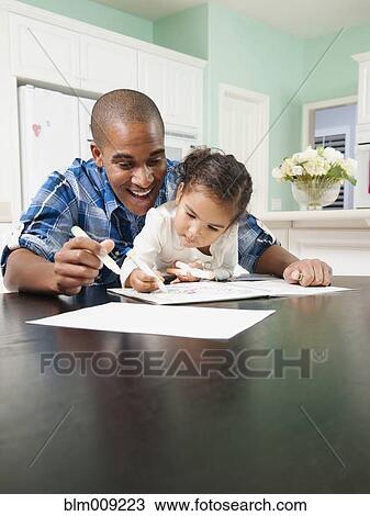 Stock Image - Father watching his daughter drawing. Fotosearch