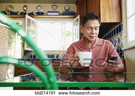 Filipino man using cell phone in kitchen View Large Photo Image Stock Image - Filipino man using cell phone in kitchen. Fotosearch