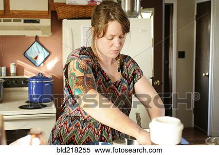 Stock Photography - Focused woman cooking in kitchen. Fotosearch