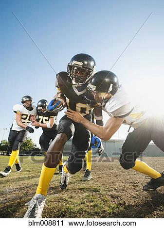 Stock Image - Football player tackling player on football field. Fotosearch