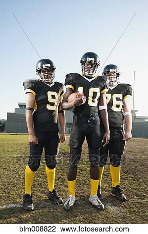 Stock Image - Football players standing on football field. Fotosearch