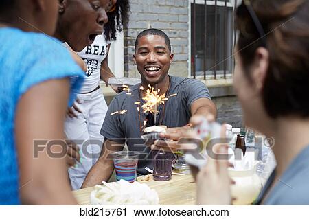 Stock Image - Friends celebrating birthday party in backyard. Fotosearch