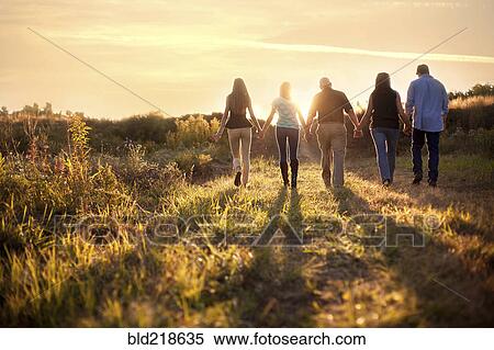 Stock Photography - Friends holding hands in sunny rural field. Fotosearch