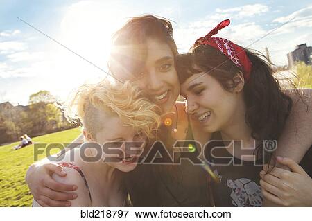 Stock Photo - Friends hugging in sunny urban park. Fotosearch