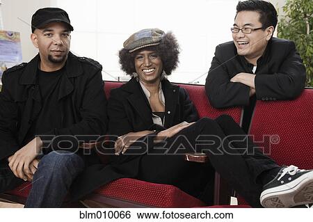 Friends relaxing on sofa together View Large Photo Image Stock Photograph - Friends relaxing on sofa together. Fotosearch