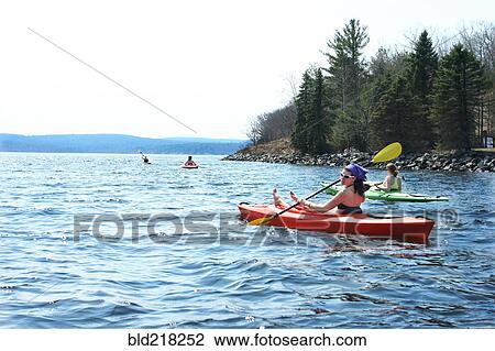 Stock Image - Friends rowing kayaks in lake. Fotosearch