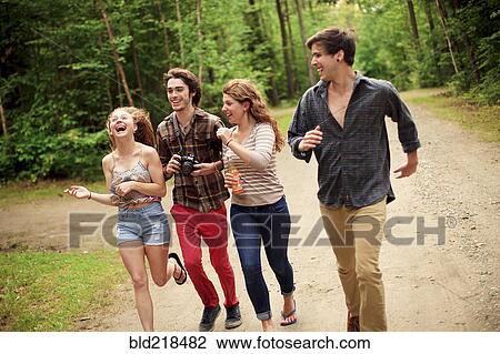 Stock Image - Friends running on dirt path in forest. Fotosearch
