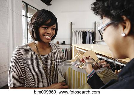 Stock Image - Friends shopping together in clothing store. Fotosearch