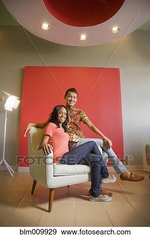Stock Photo - Friends sitting together in armchair. Fotosearch