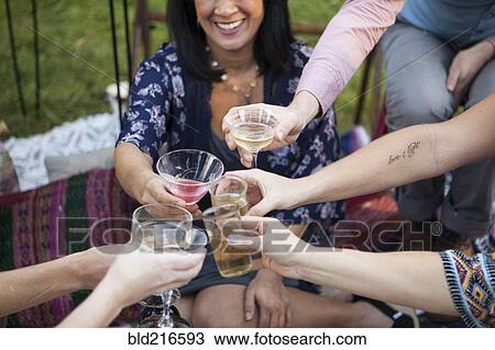 Stock Image - Friends toasting with champagne at picnic in park. Fotosearch