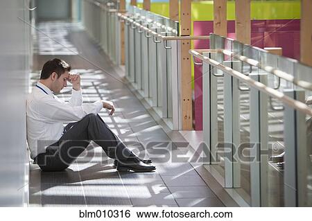 Frustrated businessman sitting on office corridor floor View Large Photo Image Stock Photograph - Frustrated businessman sitting on office corridor floor. Fotosearch