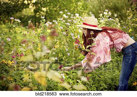 Stock Image - Gardener admiring plants in garden. Fotosearch