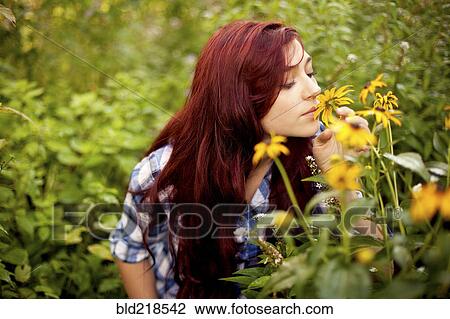 Stock Image - Gardener smelling flowers in field. Fotosearch