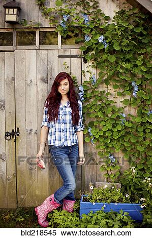 Stock Photography - Gardener standing near wooden shed in backyard. Fotosearch