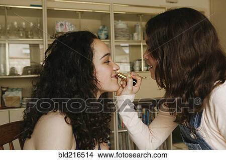 Girl applying lipstick on sister View Large Photo Image Picture - Girl applying lipstick on sister. Fotosearch
