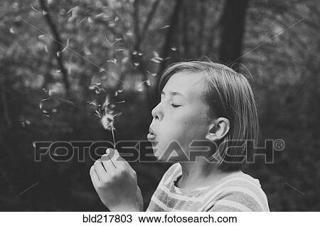 Stock Image - Girl blowing dandelion seeds. Fotosearch