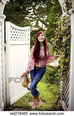 Stock Photo - Girl carrying straw hat in garden. Fotosearch