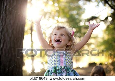 Stock Image - Girl cheering with arms outstretched on forest path. Fotosearch