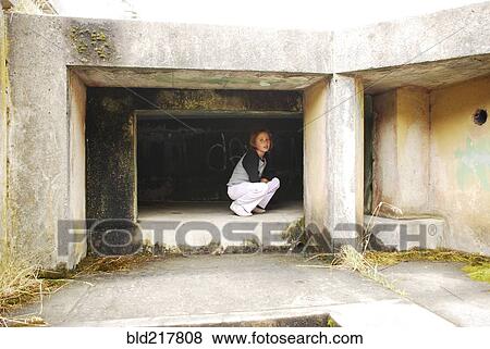 Stock Photo - Girl crouching in concrete cubby. Fotosearch