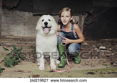 Stock Photo - Girl crouching with dog in dilapidated shed. Fotosearch