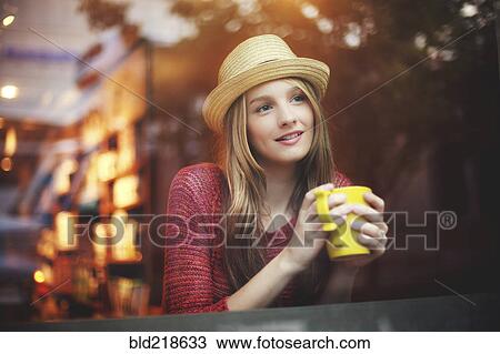 Stock Image - Girl drinking coffee in cafe near window. Fotosearch