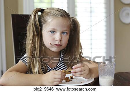 Girl eating cookie on table View Large Photo Image Stock Photograph - Girl eating cookie on table. Fotosearch
