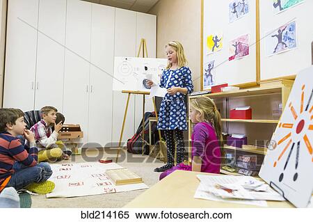 Stock Photography - Girl giving presentation to classmates. Fotosearch